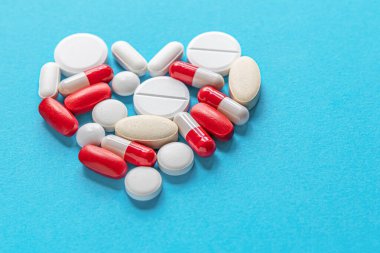  Fotokopi alanı, ilaç, sağlık, tedavi, eczane konseptine sahip mavi bir yüzey üzerinde kalp şeklinde çeşitli tabletlerin, hapların ve kapsüllerin tıbbi geçmişi