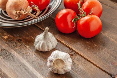 Eski ahşap bir masada domates, soğan ve sarımsak.