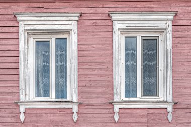 Beyaz bantlı pencereler ve eski ahşap, pembe bir evde klasik perdeler.