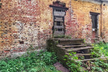 Eski püskü tuğla duvar, kilitli kapı ve terk edilmiş eski binanın ahşap verandası.