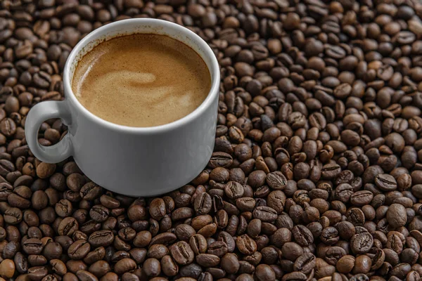 コーヒー豆の中に白磁器のカップで淹れた香り高いコーヒー — ストック写真