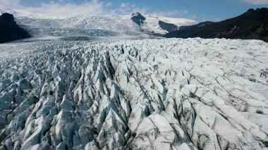 İzlanda 'nın güneydoğusundaki Fjallsjokull buzulunun muhteşem yüzeyi ve küçük buzdağlarıyla gölünün üzerindeki hava manzarası..