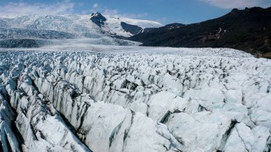 İzlanda 'nın güneydoğusundaki Fjallsjokull buzulunun muhteşem yüzeyi ve küçük buzdağlarıyla gölünün üzerindeki hava manzarası..