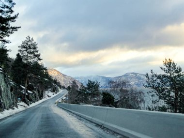 Gün doğumunda Norveç 'teki dağların ve fiyortların arasından geçmek. Yoldaki kara buz.