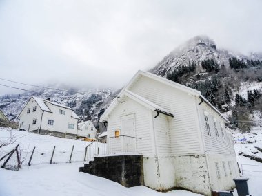 Norveç kışında beyaz ahşap evler. Kar ve dağların manzarası.