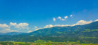 Ormanlık harika bir dağ ve Karintiya Avusturya 'da köy ve kulübeleri olan bir panorama..