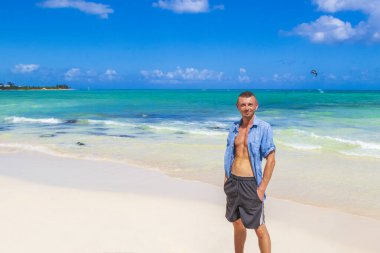 Playa del Carmen Meksika 'daki tropik Meksika plajında seksi vücutlu ve mavi gömlekli bir erkek turist..