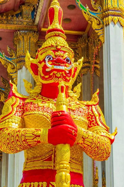 Giant temple guardian Yaksha in gold red at colorful Wat Don Mueang Phra Arramluang buddhist temple in Bangkok Thailand.