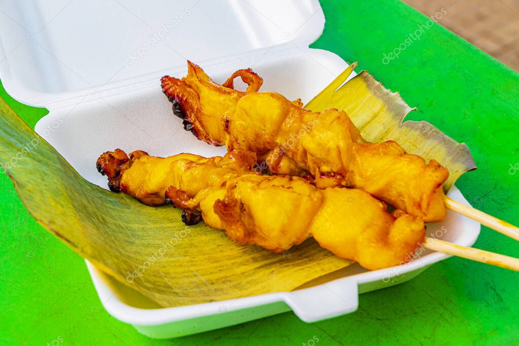 Thai food grilled chicken legs parts on skewers in banana leaf at Nai Thon Naithon Beach Phuket Thailand.