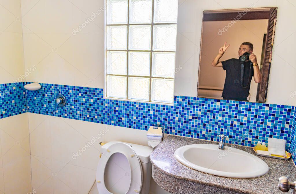 Man with camera in the mirror in a Hotel bathroom on Phuket Thailand.