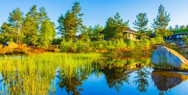 Norveç 'in doğasında, Treungen' de, Norveç 'in Treungen tatil beldesinde, nehir kıyısındaki yansımasıyla sabah güneşi..