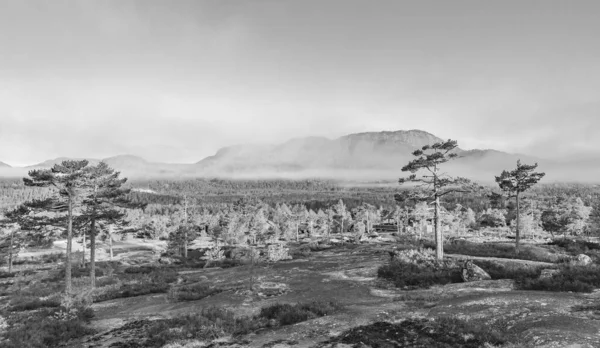 Black and white picture of morning sunrise with fog clouds and mountains in nature landscape of Treungen in Nissedal Norway.