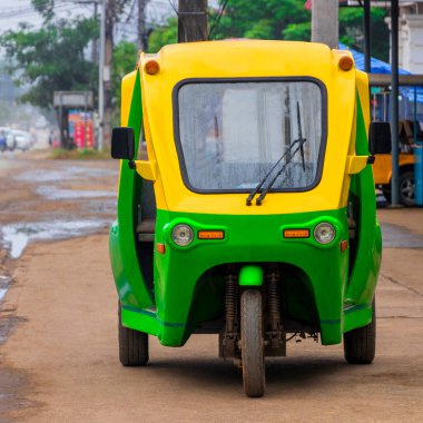 Luang Prabang Laos Asya 'daki yeşil ve sarı çevre dostu Tuk aracı rickshaw..