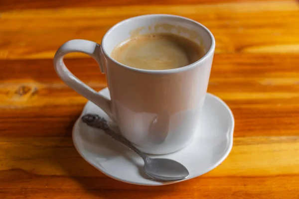 Schwarze Kaffeesahne Einer Weißen Tasse Mit Löffel Auf Einem Holztisch — Stockfoto