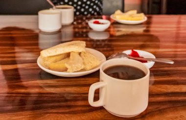 Katmandu Nepal 'deki ahşap masada reçelli ekmek ve sade kahveyle basit bir otel pansiyonu kahvaltısı..