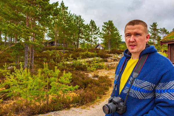 Young hiker with camera in forest of norwegian mountains and hiking trail of Treungen in Nissedal Norway.