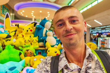 Bangkok havaalanında renkli Pokemon Pikachu oyuncakları olan bir turist..