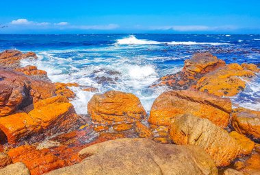 Glencairn Simons Kasabası Cape Town Batı Afrika Burnu 'nda kaya dalgaları ve bulutlu dağlarla sahte körfez manzarası.