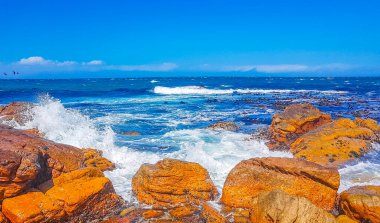 Glencairn Simons Kasabası Cape Town Batı Afrika Burnu 'nda kaya dalgaları ve bulutlu dağlarla sahte körfez manzarası.