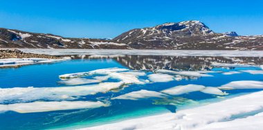 Yaz manzarasında donmuş turkuaz göl Vavatn manzarası ve Hemsedal Norveç 'te karlı dağlar.
