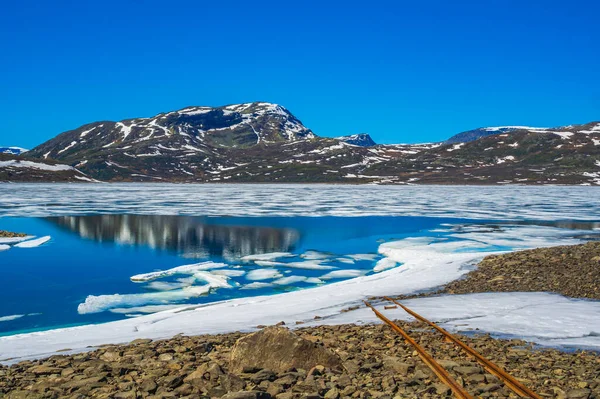 氷結したターコイズブルーの湖の水につながる古いレールヘムゼダルノルウェーのVavat風景 — ストック写真