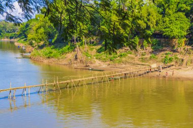 Laos halkı Luang Prabang Laos 'taki Mekong Nehri' ndeki Bambu Köprüsü 'nde yüzüyor..