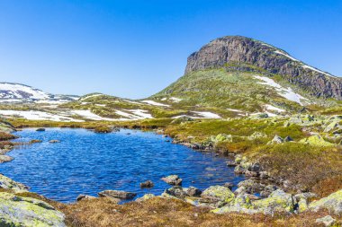 Hemsedal Norveç 'teki Hydnefossen şelalesinin yanındaki Veslehdn Veslehorn Dağı' nın tepelerine ve kayalara çarpar.