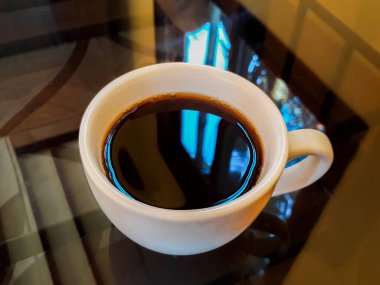 Luang Prabang Laos 'ta siyah cam bir masa üzerinde beyaz bir fincanda koyu kahve kreması..