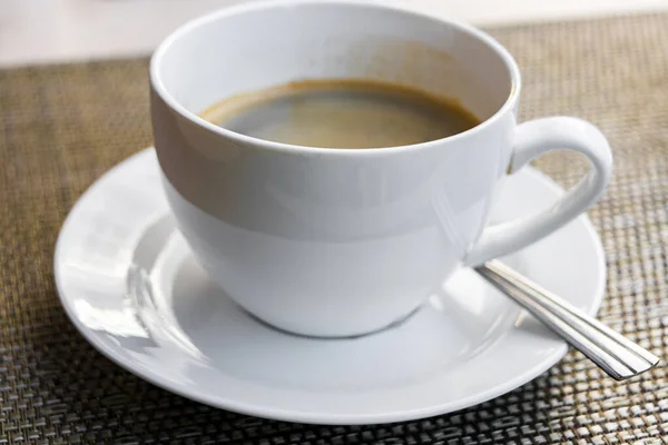 Schwarze Kaffeesahne Einer Weißen Tasse Mit Löffel Auf Einem Tisch — Stockfoto