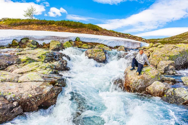 Gezgin turist, Hemsedal Norveç 'teki yaz manzarasında Vavatn Gölü' nün yanındaki Storebottane nehrinde oturur..