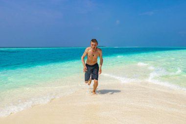 Komik Rus turist gezgini, Rasdhoo Mercan Maldivleri 'ndeki Madivaru ve Finolhu adalarında renkli suda koşuyor..