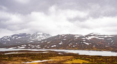 Vavatn Gölü manzarası inanılmaz engebeli kaya ve dağları Hemsedal Norveç 'te yaz boyunca karla kaplı.