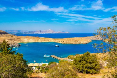 Lindos Sahili panorama manzarası turkuaz berrak su botu turistleri ve Rodos Yunanistan 'da güneş görüyor.