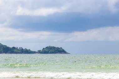 Patong Beach bay sea coast panorama view with turquoise blue clear water waves white sand and green mountains and palm trees in Patong Beach Kathu District Phuket Island Province Southern Thailand.
