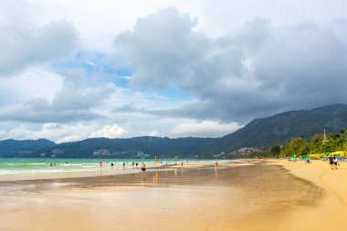 Kathu Phuket Thailand 08. October 2025 Patong Beach bay sea coast panorama view with promenade tourists people turquoise blue clear water waves and green mountains and palm trees in Patong Thailand.