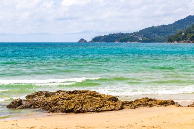 Patong Beach bay sea coast panorama view with turquoise blue clear water waves white sand and green mountains and palm trees in Patong Beach Kathu District Phuket Island Province Southern Thailand.