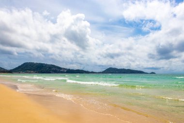 Patong Beach bay sea coast panorama view with turquoise blue clear water waves white sand and green mountains and palm trees in Patong Beach Kathu District Phuket Island Province Southern Thailand.