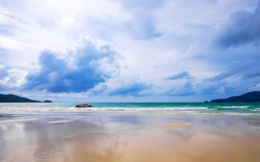 Patong Beach bay sea coast panorama view with turquoise blue clear water waves white sand and green mountains and palm trees in Patong Beach Kathu District Phuket Island Province Southern Thailand.