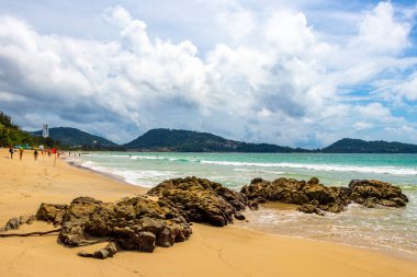 Patong Beach bay sea coast panorama view with turquoise blue clear water waves white sand and green mountains and palm trees in Patong Beach Kathu District Phuket Island Province Southern Thailand.
