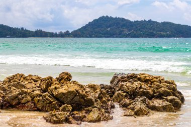 Patong Beach bay sea coast panorama view with turquoise blue clear water waves white sand and green mountains and palm trees in Patong Beach Kathu District Phuket Island Province Southern Thailand.