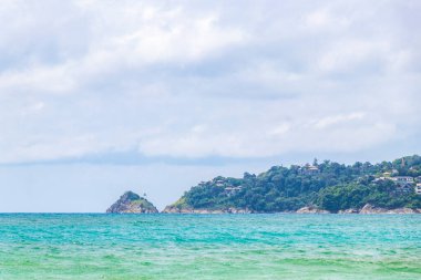 Patong Beach bay sea coast panorama view with turquoise blue clear water waves white sand and green mountains and palm trees in Patong Beach Kathu District Phuket Island Province Southern Thailand.