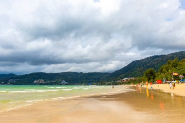 Kathu Phuket Thailand 08. October 2025 Patong Beach bay sea coast panorama view with promenade tourists people turquoise blue clear water waves and green mountains and palm trees in Patong Thailand.