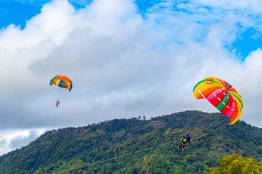 Kathu Phuket Thailand 10. October 2025 Patong Beach bay sea coast panorama view with people tourism and parasailing parachute sport activity water waves mountains and clouds in Patong Phuket Thailand.