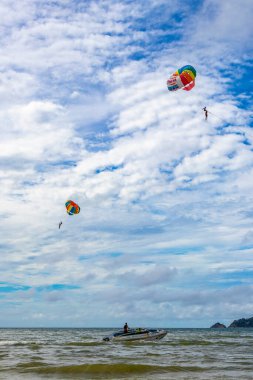 Kathu Phuket Thailand 10. October 2025 Patong Beach bay sea coast panorama view with people tourism and parasailing parachute sport activity water waves mountains and clouds in Patong Phuket Thailand.