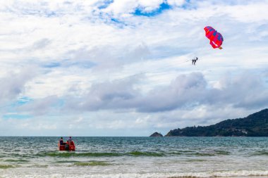 Kathu Phuket Thailand 10. October 2025 Patong Beach bay sea coast panorama view with people tourism and parasailing parachute sport activity water waves mountains and clouds in Patong Phuket Thailand.
