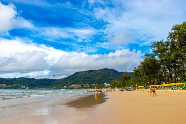 Kathu Phuket Tayland 10 numara. Ekim 2025 Patong Sahili sahil manzaralı gezinti turistleri açık mavi su dalgaları ve yeşil dağlar ve Patong Tayland 'daki palmiye ağaçları..