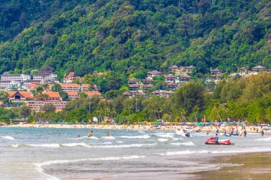 Kathu Phuket Tayland 10 numara. Ekim 2025 Patong Sahili sahil manzaralı gezinti turistleri açık mavi su dalgaları ve yeşil dağlar ve Patong Tayland 'daki palmiye ağaçları..