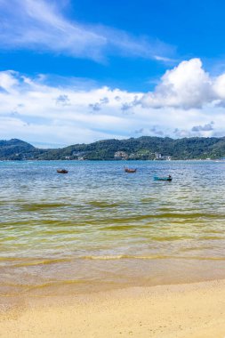 Patong Beach bay sea coast panorama view with turquoise blue clear water waves white sand and green mountains and palm trees in Patong Beach Kathu District Phuket Island Province Southern Thailand.