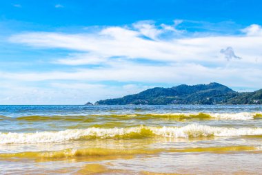 Patong Beach bay sea coast panorama view with turquoise blue clear water waves white sand and green mountains and palm trees in Patong Beach Kathu District Phuket Island Province Southern Thailand.