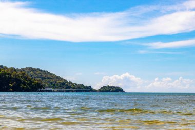 Patong Beach bay sea coast panorama view with turquoise blue clear water waves white sand and green mountains and palm trees in Patong Beach Kathu District Phuket Island Province Southern Thailand.